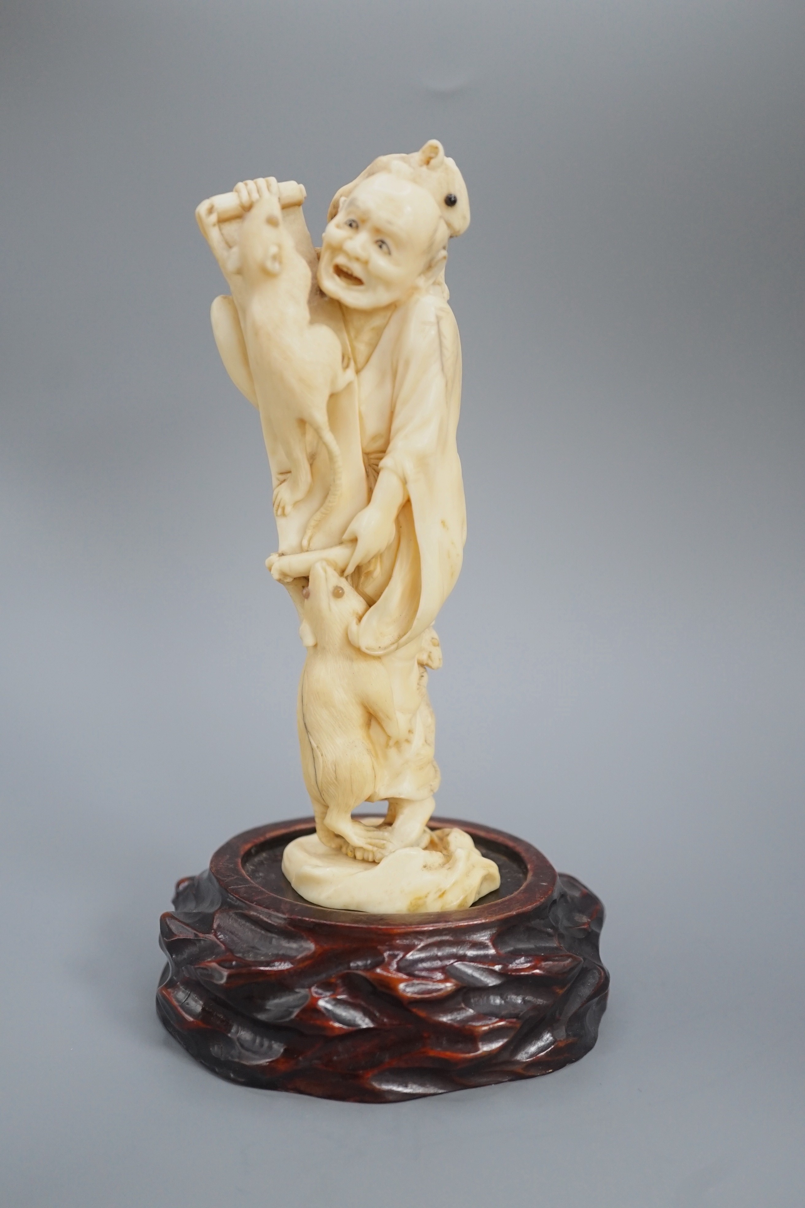 A Japanese ivory okimono of a man with giant rats clambering over him, signed, late 19th century 12.5cm, wood stand